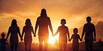 Adults and children standing together at sunset.