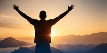 A person facing a new sunrise over a mountain landscape.